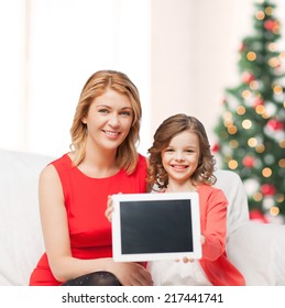 christmas, x-mas, happiness, advertisement concept - mother and daughter with tablet pc showing blank screen