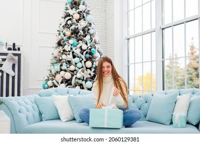 christmas, x-mas, winter, happiness concept - smiling woman with many gift boxes. Girl opens a gift against the background of the Christmas tree. happy young woman celebrating Christmas - Powered by Shutterstock