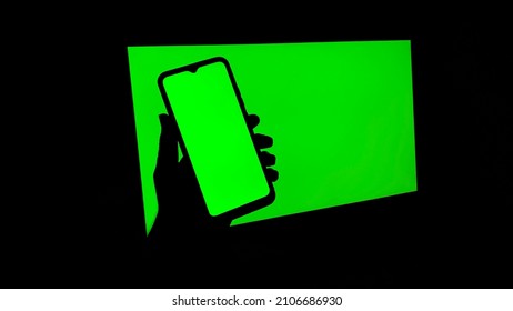 Chroma Key On Electronic Devices, Phone And Monitor, Green Screen And Hand Scrolling Through The Screen In The Absence Of Light