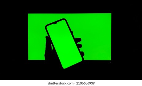 Chroma Key On Electronic Devices, Phone And Monitor, Green Screen And Hand Scrolling Through The Screen In The Absence Of Light