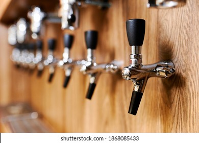 Chrome Beer Taps In A Row On Wooden Wall.