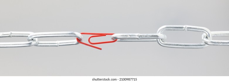 Chrome chain in middle with red paper clip. Broken chain linked by paper clip concept