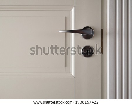 Chrome handle with keyhole on white door with panels in frames. Entrance. Close-up photo of architecture detail. Interior fragment as geometrical background with three rectangles and parallel lines.