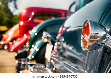 Chrome rear tail lights and vintage cars on display.