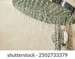 Chrome shower head with water droplets streaming from it. The image captures the refreshing and invigorating feeling of a shower