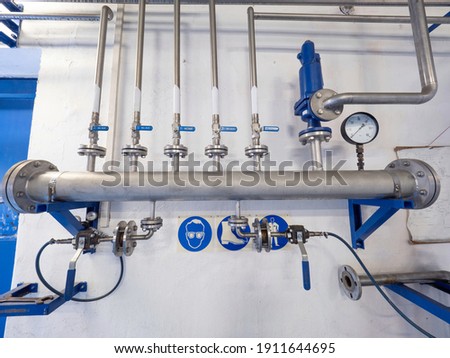 Chrome steel gas pipes with ball valves and fittings on the wall. The main bio methane pipeline with thin branches.