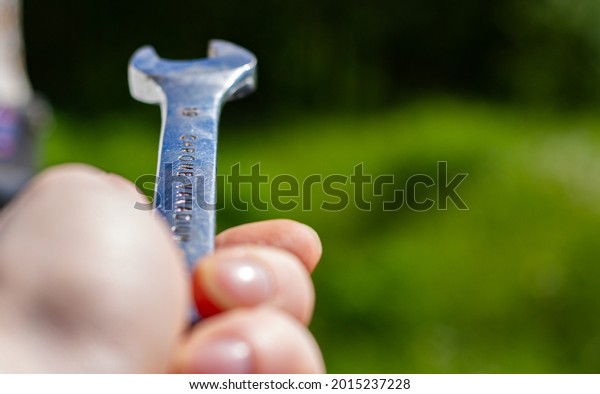 Chrome wrench in hand, shallow depth of\
field, blurred\
background.