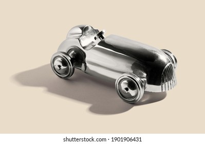 Chromed silver vintage two sealer open sports car toy with integral wheels, on a white beige with shadow