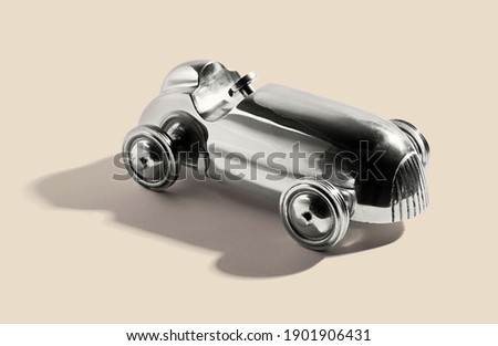 Chromed silver vintage two sealer open sports car toy with integral wheels, on a white beige with shadow