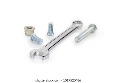 Chrome-plated combination wrench open at one end and ring at the other among of bolts, screws, nuts at selective focus on a white background
