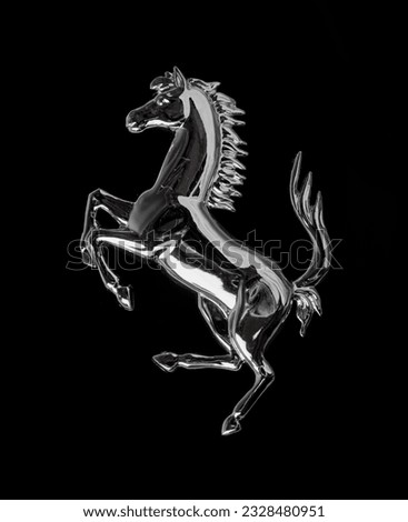 The chrome-plated horse stands on its hind legs against a black background. Beautiful tail raised high

