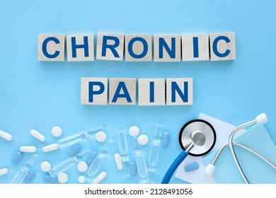 CHRONIC PAIN Text On Wooden Cubes On A Blue Background. Ampoules Pills Stethoscope