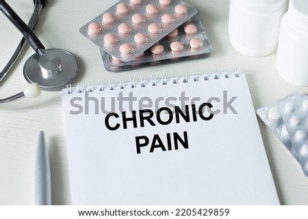 CHRONIC PAIN is written in a white notebook. Medical concept