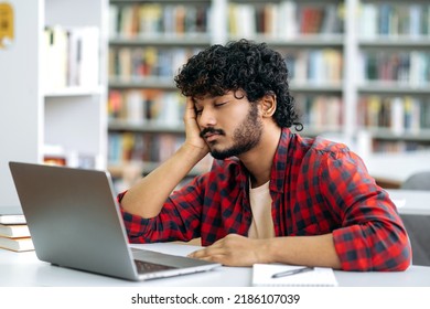 Chronic Sleep Deprivation. Tired Bored Arabian Or Indian University Student, Is Sleeping While Sitting At Desk In Library, Exhausted Of Learning, Preparing For Exam Session, Suffering Of Lack Of