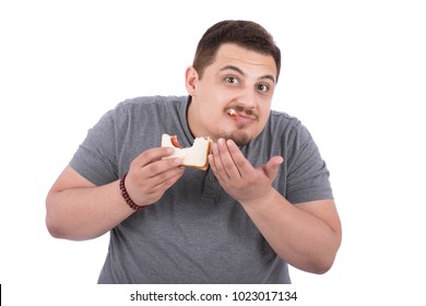 A chubby man eats a sandwich and the strawberry jam dropped down from his mouth, isolated on a white background.