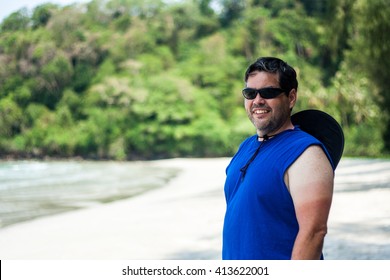 Chubby Man Wearing Sunglasses And Standing On The Beach And Smiling To You