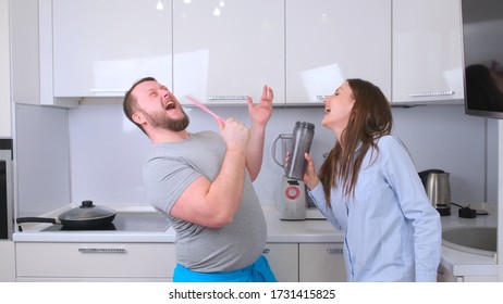 Chubby Man And Woman Dancing And Singing In The Kitchen While Cooking At Home, The Concept Of A Happy Fun Family.