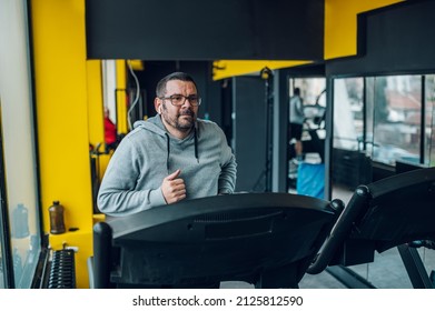 Chubby Middle Aged Man Walking On Running Track. Running On A Treadmill. Overweight.