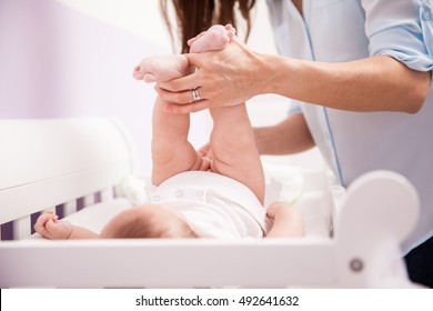 Chubby Newborn Baby With Her Legs Up Getting Her Diaper Changed By Her Mother In The Nursery Room