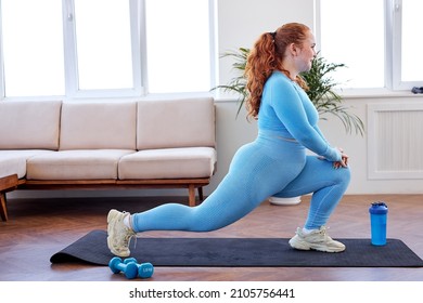 Chubby Redhead Woman Doing Lunges On Mat, Engaged In Fitness, At Home, Wearing Blue Sportive Outfit, Stretching Body, Warming Up Muscles, Lead Healthy Lifestyle. Oversize Plus Size Model Workout