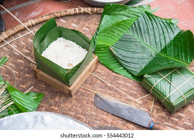 Chung Cake ingredients, tool preparation wrapping. Square shape wood mold with glutinous rice, split mung beans, chunks of pork shoulder, salt, pepper, ginger, bamboo, banana leaves, long node string.