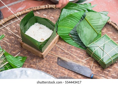 Chung Cake ingredients, tool preparation wrapping. Square shape wood mold with glutinous rice, split mung beans, chunks of pork shoulder, salt, pepper, ginger, bamboo, banana leaves, long node string.