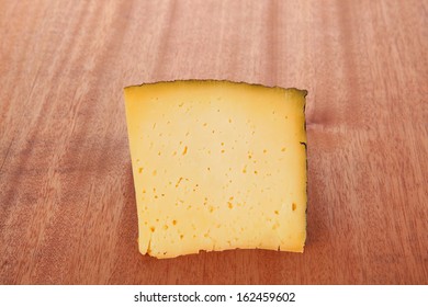 Chunk Of Aged French Gruyere Or Cheddar Cheese In Black Shell On Wooden Table