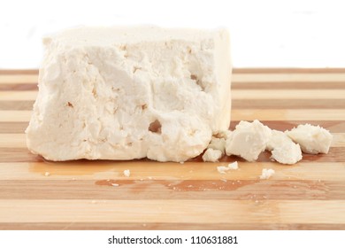 Chunk Of Feta Cheese With Crumbles On A Wooden Board