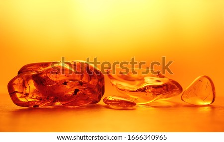 Chunks of amber in the yellow background light. An abstract pattern. Close up, blurred background. Selective focus, emphasis on the left stone. Negative space. Beautiful background, wallpaper.