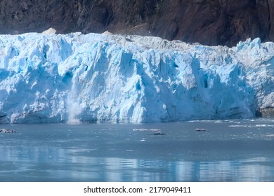 Chunks of ice fall off the face of a glacier into the sea