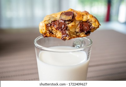 Chunky Chewy Chocolate Chip Soft Cookie On Cold White Milk In Cup For Breakfast, Selective Focus On Melting Chocolate Chips