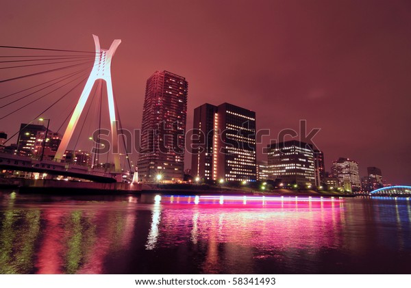 Chuo-Ohashi suspension\
bridge in Tokyo, Japan with light traces of moving passenger ship\
by night time