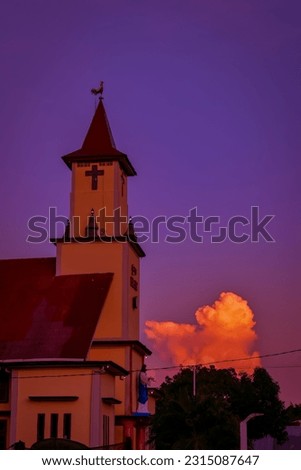 Church building tower against orange sky background