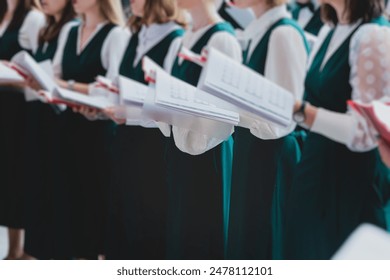 Church choir concert in cathedral, choral artists singing, group of European boys and girls singing in a chorus, students and choristers in white and green uniform performing on stage with conductor - Powered by Shutterstock