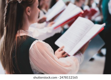 Church choir concert in cathedral, choral artists singing, group of European boys and girls singing in a chorus, students and choristers in white and green uniform performing on stage with conductor - Powered by Shutterstock