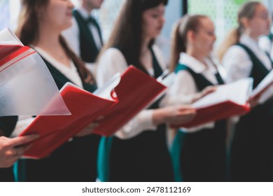 Church choir concert in cathedral, choral artists singing, group of European boys and girls singing in a chorus, students and choristers in white and green uniform performing on stage with conductor - Powered by Shutterstock