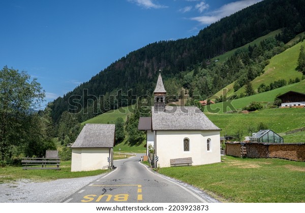 A church divided in two by a road. The location is\
in Trentino, Italy.