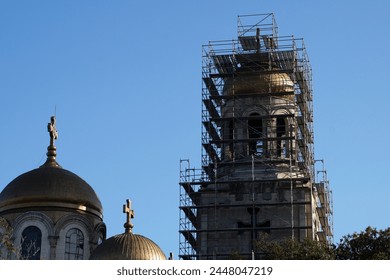 church domes under renovation with construction scaffolding against sky.