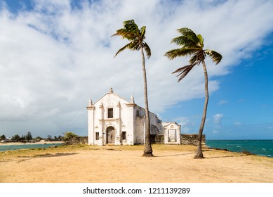Church and fortress of San Antonio on Mozambique island, with two palm trees on sand. Indian ocean coast, Nampula province, Mozambique. Fortim de Santo António na Ilha de Moçambique. 