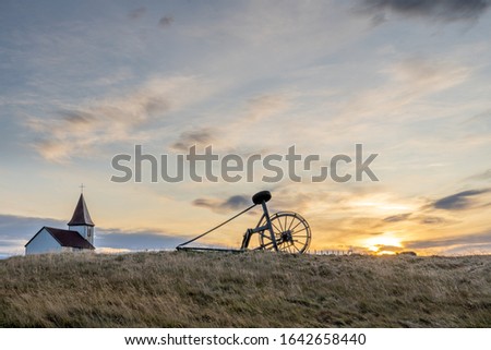 Church of Hellnar with Old Haymaking Machine (tractor) on grass field sunset time