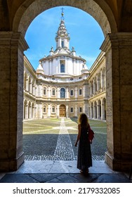 Church Of Saint Yves At La Sapienza, Rome, Italy. Girl Tourist Visits Former University Of Rome. Person, Young Woman Looks At City Landmark. Concept Of Sightseeing, Tourism And Travel People In Rome.