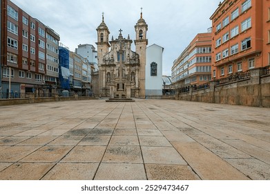 The Church of San Jorge stands in a quiet urban square in La Coruña, Spain, baroque architecture. The surrounding modern buildings create a striking contrast with the historic church facade. - Powered by Shutterstock