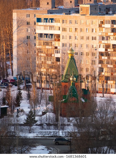 Church of the Savior Not Made by Hands in Omsk at\
Mendeleev Avenue 1/1. Brick temple with green pyramidal domes and\
golden domes with a cross on top. A temple among nine-story\
buildings and roads.