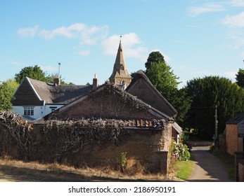 Church Spire Rising Above Village Houses With Trees And Blue Sky.     