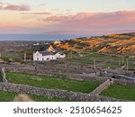 Church surrounded by stone walls in Inis Meáin with sunset and pink sky, Aran Islands, County Galway, Ireland