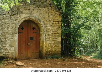 church in the woods. Chapel in a forest. Entrance door to a church in the forest. Path leading to a forest chapel. Hermitage. Place of spirituality.