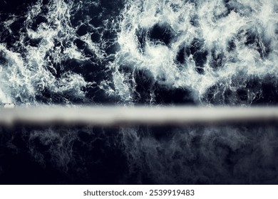 Churning waves create swirling patterns in deep blue water, evoking a sense of movement and energy.