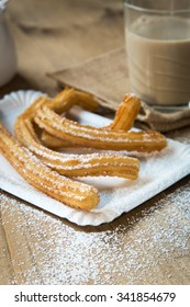 Churros with coffee with milk and sugar on old wooden table