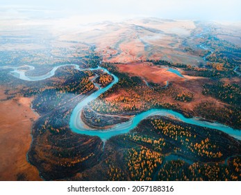 Chuya river in Kurai steppe, Altai mountains, Siberia, Russia. Aerial drone view. Blue river with yellow autumn trees with morning fog. Beautiful autumn landscape.