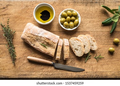 Ciabatta - Fresh Homemade Italian Bread, olives and olive oil on wooden table, top view. - Powered by Shutterstock